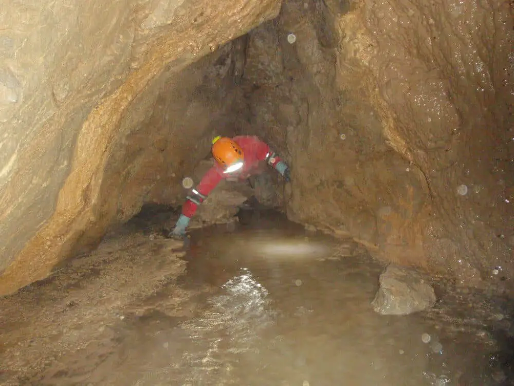 Caver squeezing through a narrow passage