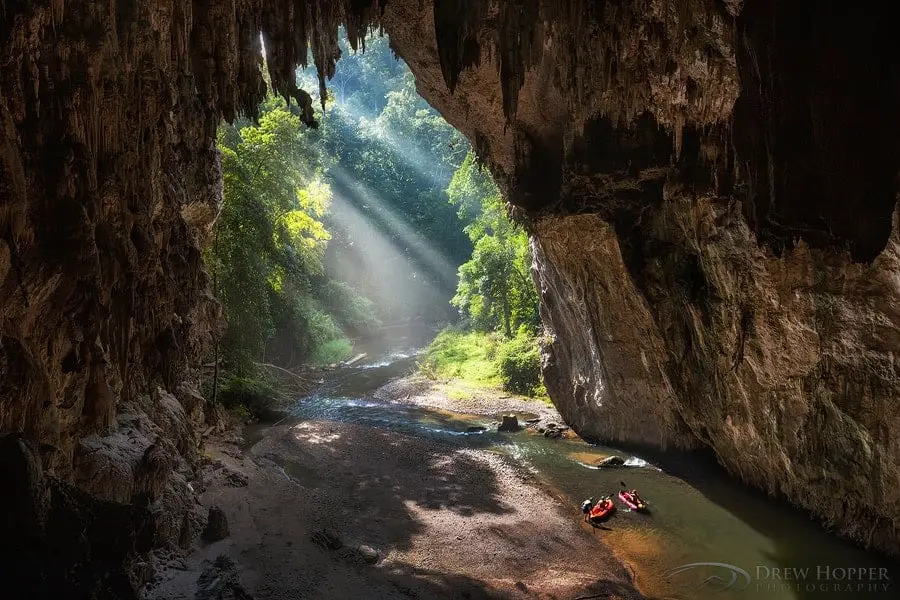 High cave entrance with rays of light and jungle